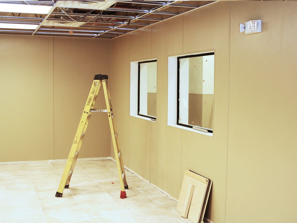 A ladder in the middle of a room with windows.