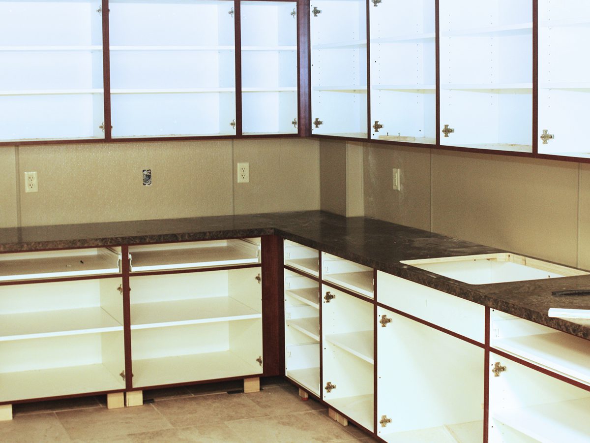 A kitchen with white cabinets and glass doors.