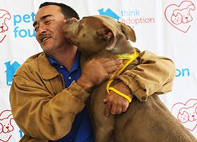 A man holding his dog in front of him.
