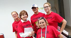 A group of people wearing red shirts and smiling.