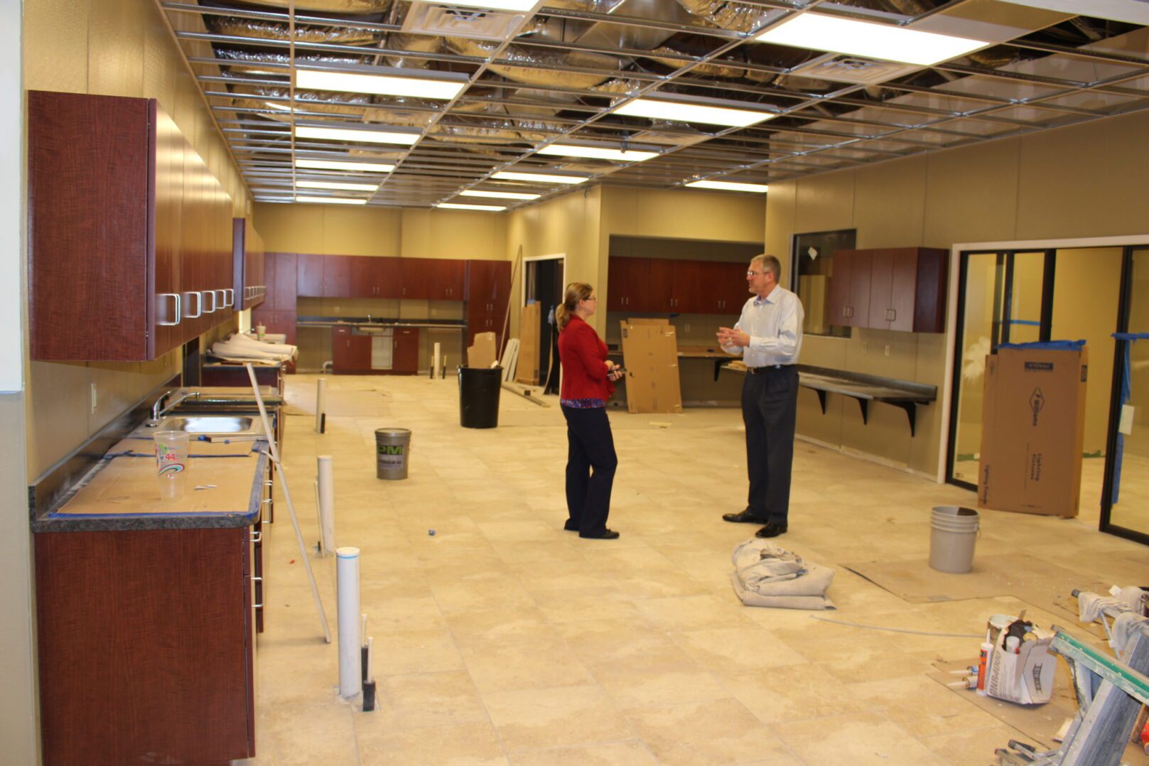 Two people standing in a room with some cabinets