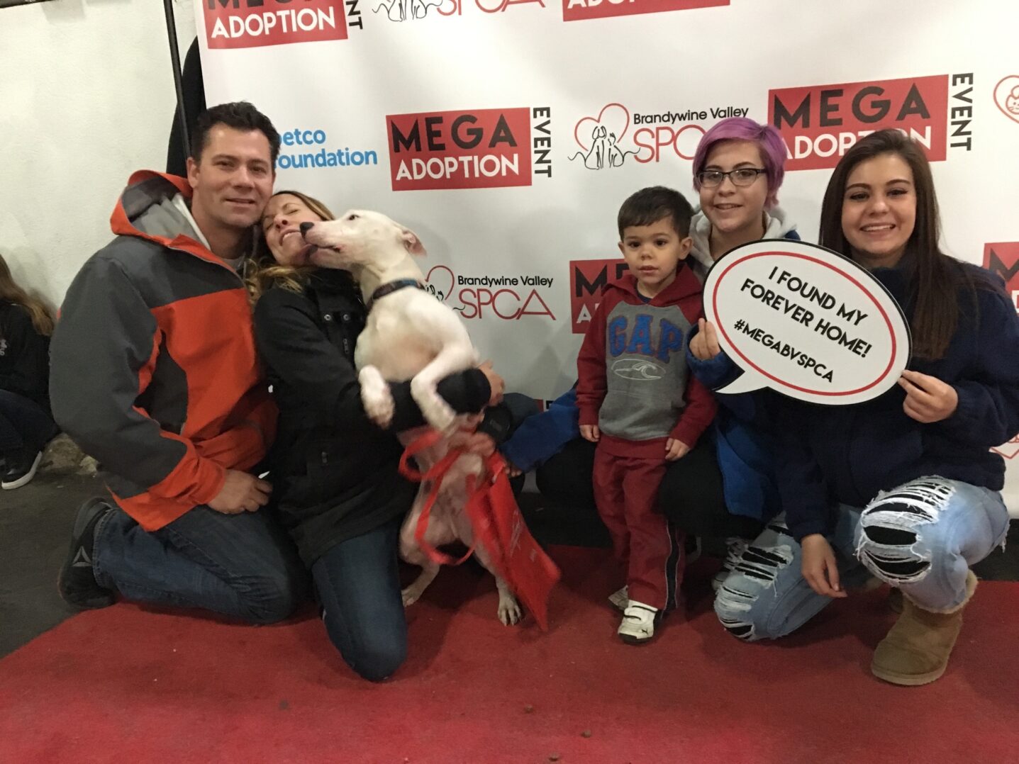 A group of people posing for the camera with a dog.