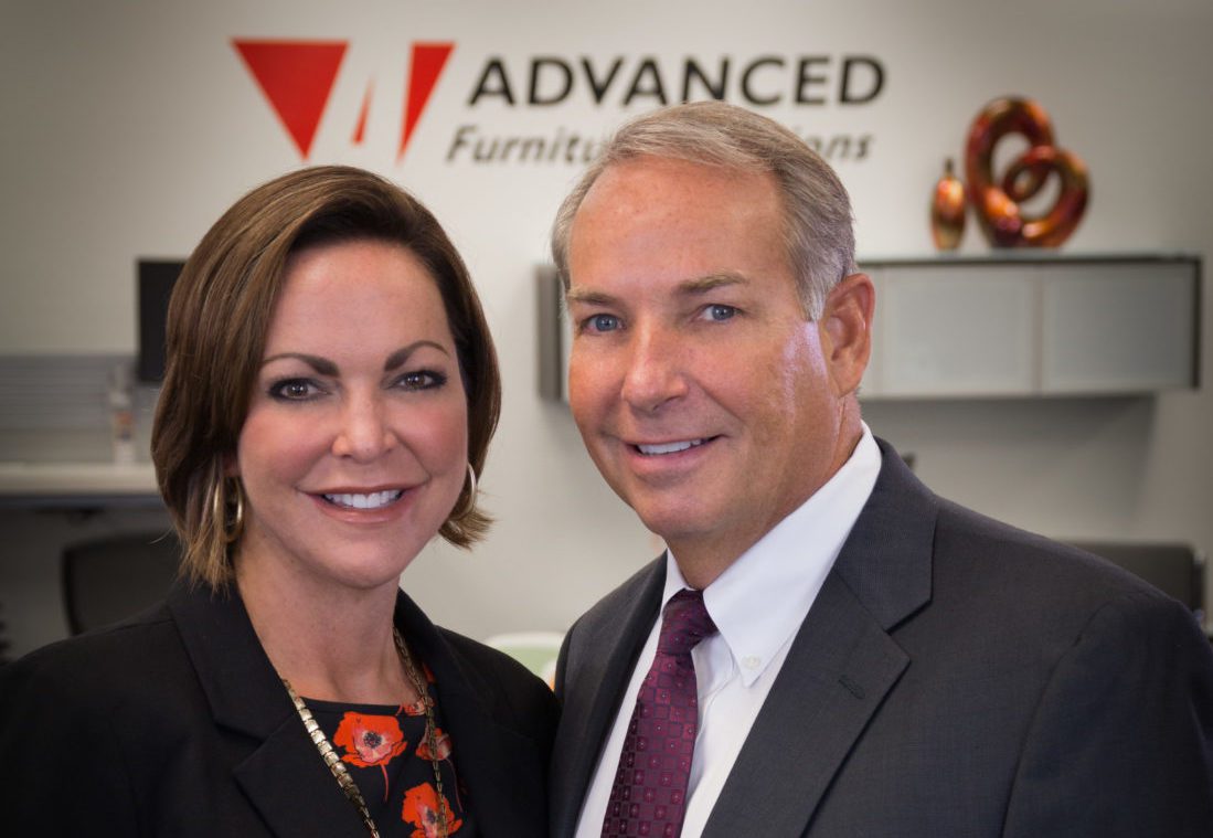 A man and woman standing in front of a sign.