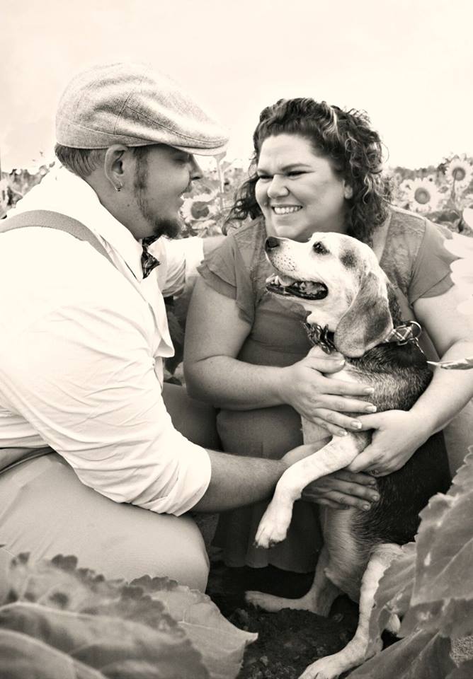 A man and woman holding a dog in their arms.